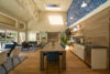 Large open plan room with long wood table with 10 chairs and lounge seating and kitchen