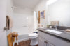 Grey stone sink vanity with large mirror and shower tub.