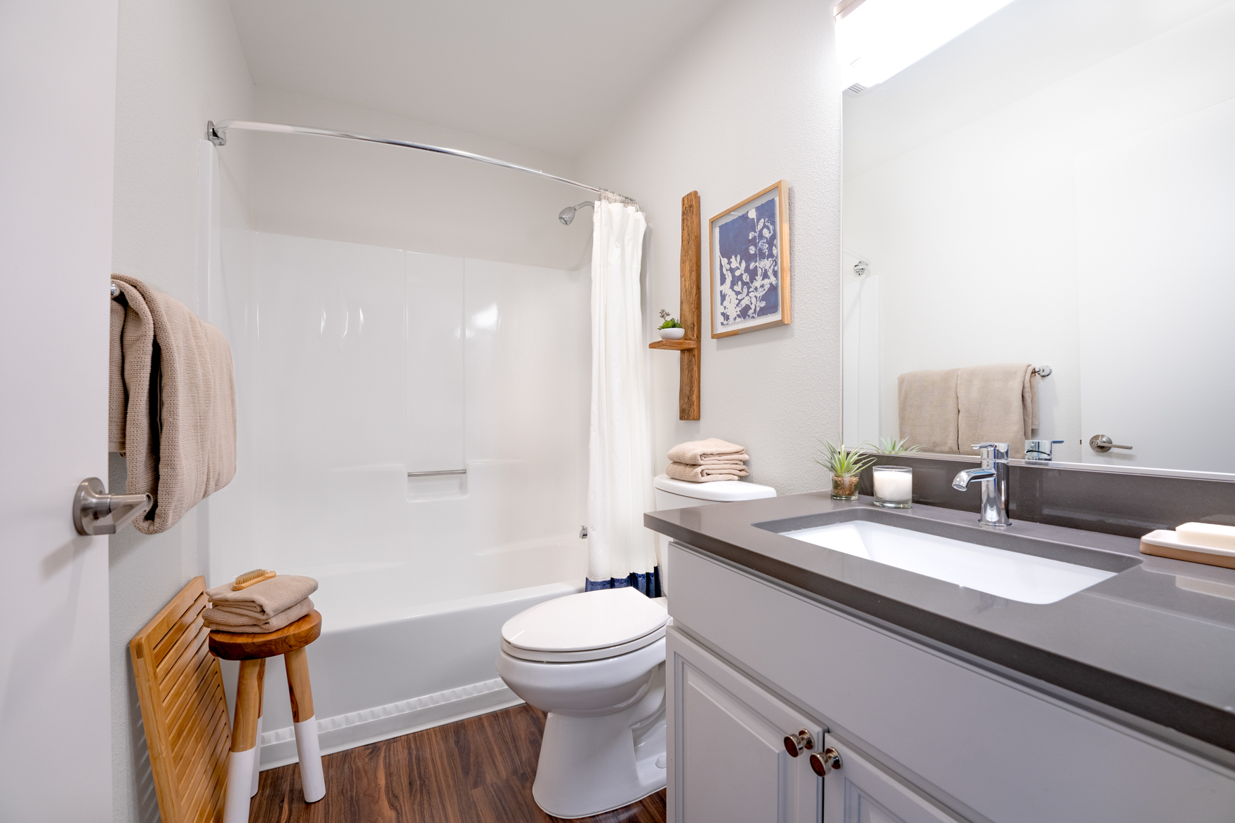 Grey stone sink vanity with large mirror and shower tub.