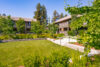 Lush green shrubs and leafy trees around a grassy lawn.