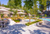 Spacious outdoor pool area with sun loungers and spa surrounded by 2 story apartments