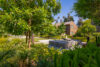 Stone water fountain in front of grassy tree lined area and 2 story apartment buildings.